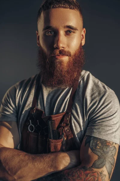 Уверенный бородатый парикмахер смотрит в камеру — стоковое фото