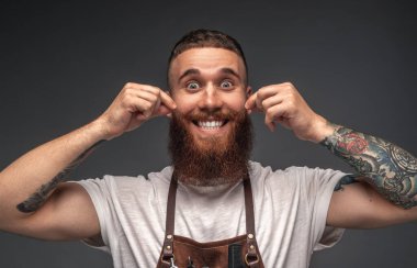 Komik berber bıyığı buruyor ve gülümsüyor.