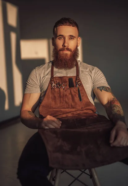 Serious barber sitting on stool — Stock Photo, Image