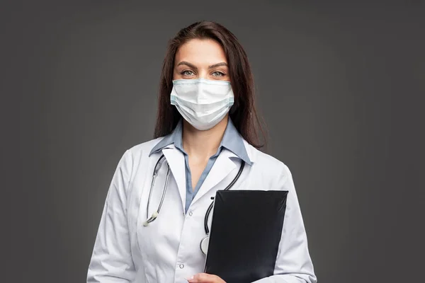 Médica feminina em máscara facial com prancheta — Fotografia de Stock
