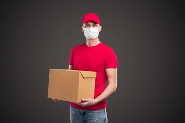 Koruyucu maskeli erkek kurye paket taşıyor.