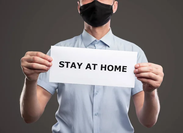 Pria bertopeng memegang kertas dengan "Stay At Home text" — Stok Foto