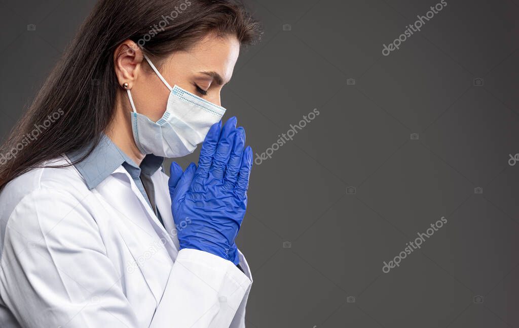 Female doctor praying during pandemic