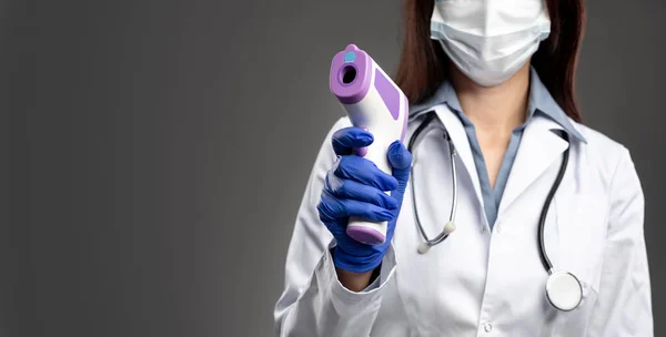 Медсестра с инфракрасным термометром — стоковое фото