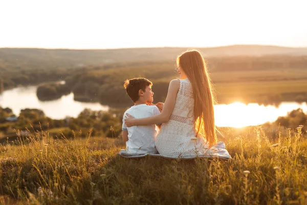 Glada syskon vilar på kvällslandskapet — Stockfoto