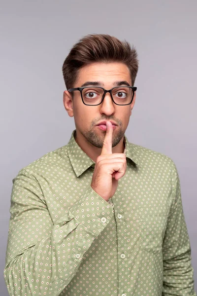 Young man telling secret and keeping forefinger on lips — Stock Photo, Image