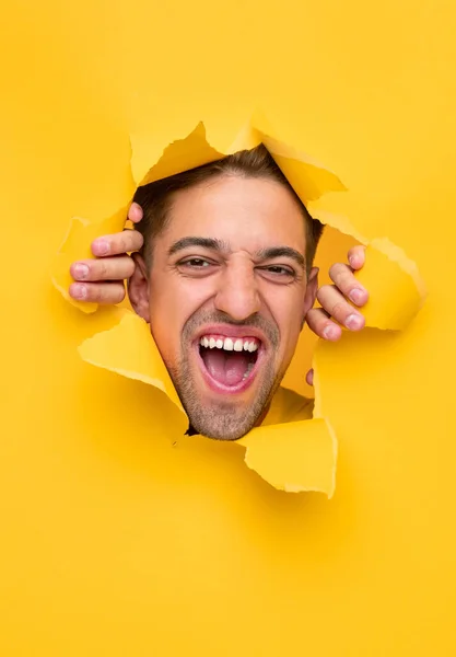 Angry man tearing yellow paper — Stock Photo, Image