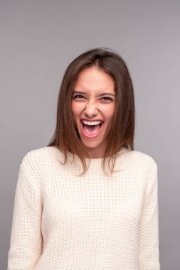 Beyaz kazaklı, heyecanlı esmer, kameraya bakıyor.