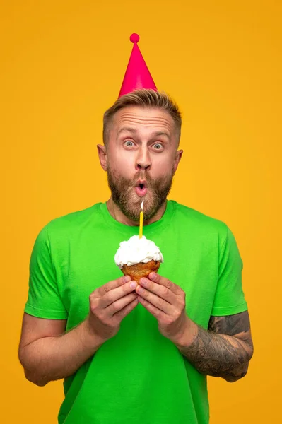 Engraçado masculino soprando vela no cupcake — Fotografia de Stock