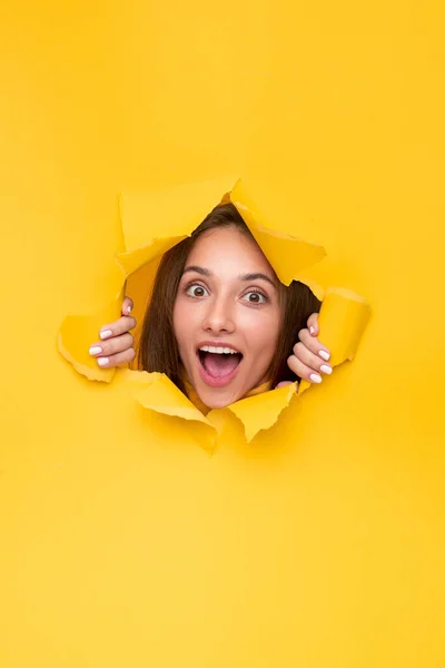 Mulher excitada espreitando papel rasgado — Fotografia de Stock