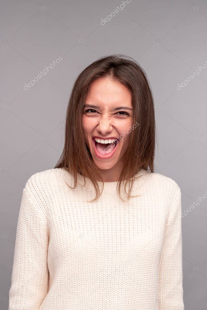 Excited brunette in white sweater looking at camera