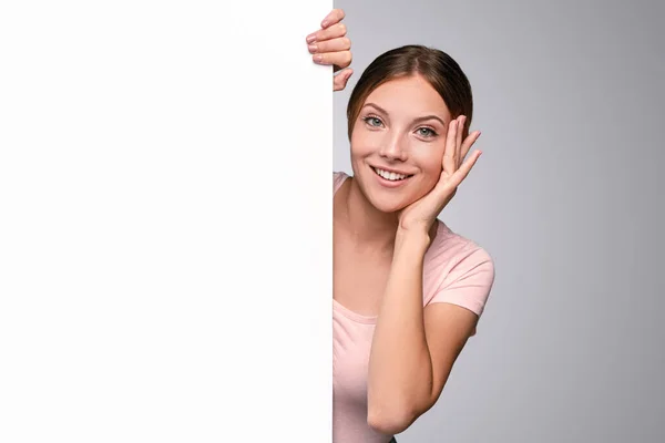 Sorrindo mulher espreitando por trás bandeira branca — Fotografia de Stock