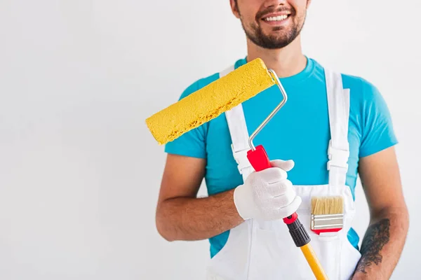 Happy worker with painting tools against white wall — Stock Photo, Image