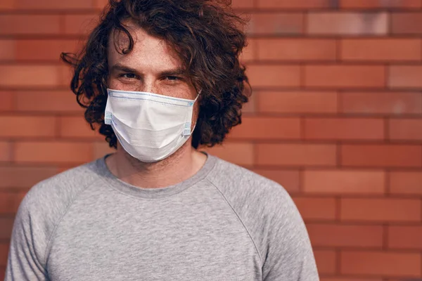 Людина в медичній масці проти цегляної стіни — стокове фото