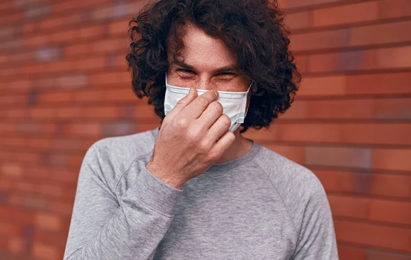 Homem alegre ajustando máscara durante a epidemia — Fotografia de Stock