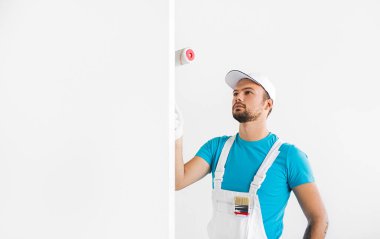 Ciddi bir erkek müteahhit duvar boyuyor.