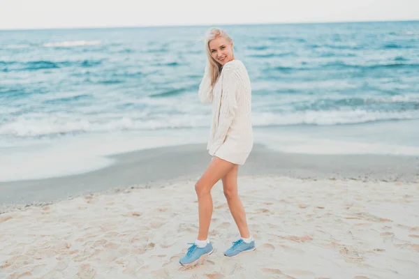 ผู้หญิงสาวที่มีความสุขในชุดสีขาวยืนบนชายหาดทราย — ภาพถ่ายสต็อก