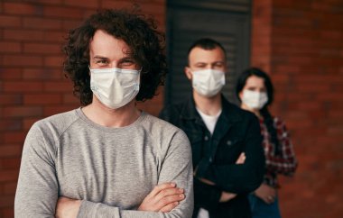 Arkadaşlarının yanında duran maskeli adam.