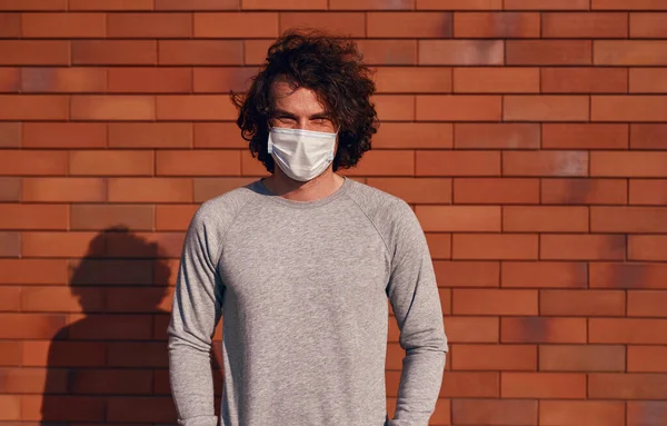 Людина в медичній масці біля цегляної стіни — стокове фото