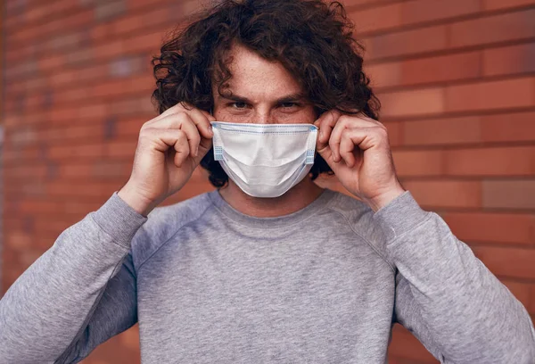 Un tânăr care pune o mască medicală pe stradă — Fotografie, imagine de stoc