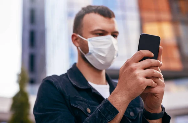 Bărbat în mască medicală folosind smartphone-ul pe stradă — Fotografie, imagine de stoc