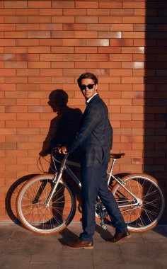 Erkek müdür sokakta bisiklet park ediyor.