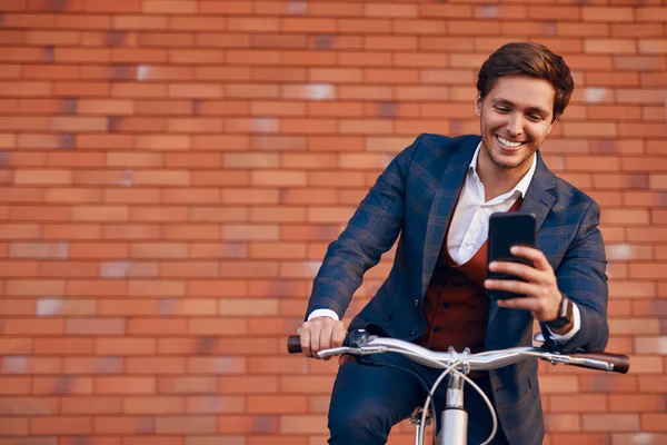 자전거를 타고 길에서 스마트폰을 사용하는 행복 한 사업가 — 스톡 사진