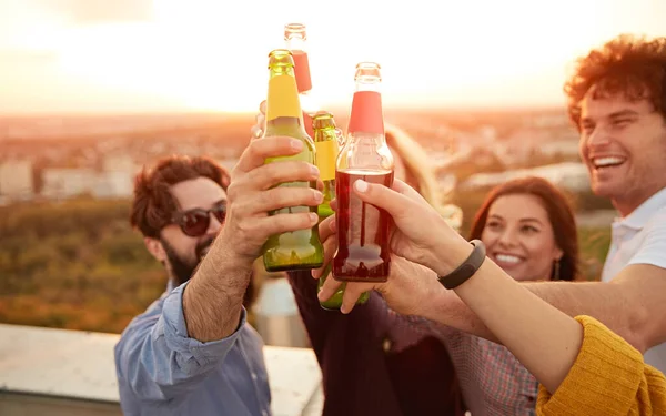 Gruppo di amici allegri che strizzano le bottiglie durante la festa estiva — Foto Stock
