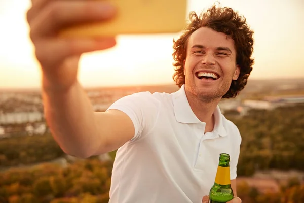 Ragazzo allegro con birra scattare selfie durante la festa — Foto Stock