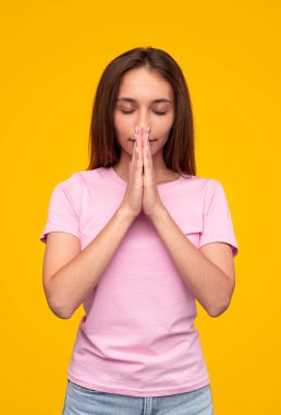 Genç bir dişi dua ederken ellerini sımsıkı tutuyor.