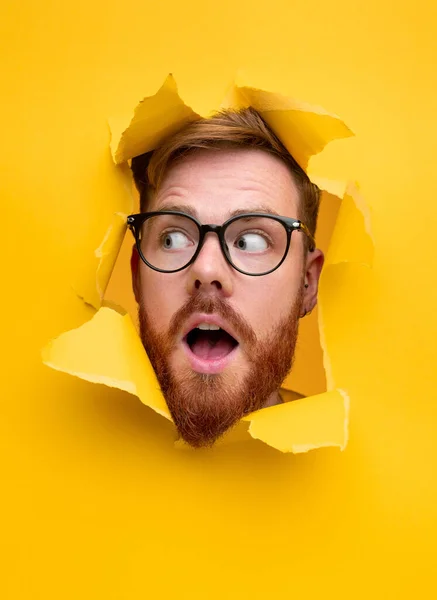 Shocked ginger man in torn paper hole — Stock Photo, Image