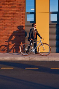 Bisikletle sokakta yürüyen mutlu bir yönetici.