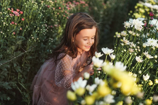Menina cheirando flores no jardim — Fotografia de Stock