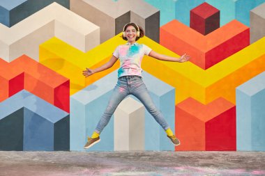 Mutlu kadın boya festivalinde müzik dinliyor ve zıplıyor.