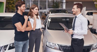 Araba galerisinde müşterilerle çalışan bir erkek yönetici.