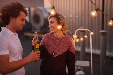 Parti boyunca bira içip sohbet eden neşeli bir çift.