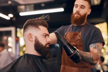 Bulanık berber müşterinin saçlarını kurutuyor.