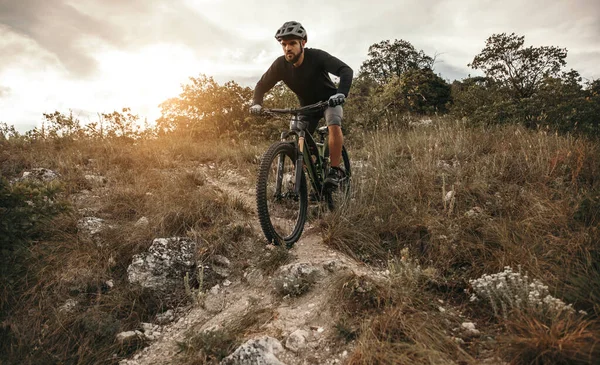 Barbuto uomo in sella mountain bike durante il tramonto — Foto Stock