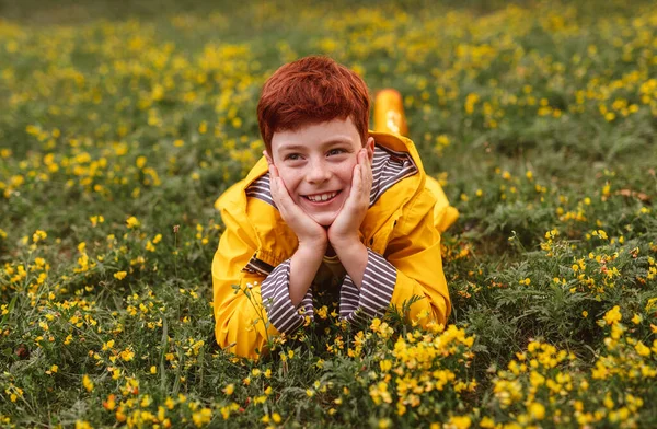 Menino feliz deitado no campo florescente — Fotografia de Stock