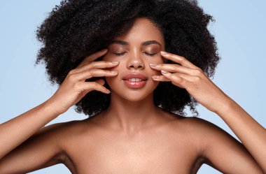 Afrikalı Amerikalı kadın yanaklarına krem sürüyor.