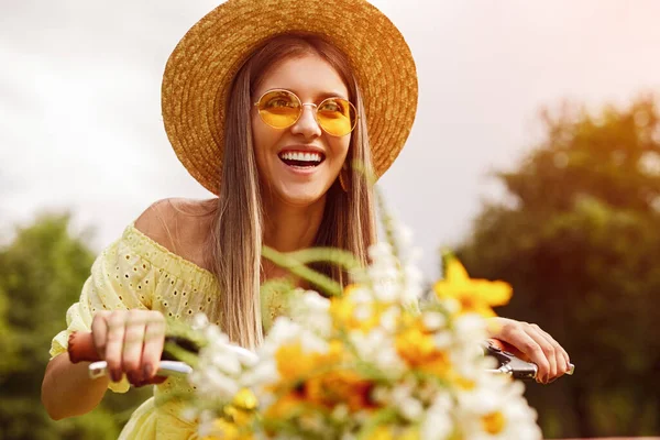 Ευτυχισμένη γυναίκα ιππασία ποδήλατο με λουλούδια — Φωτογραφία Αρχείου
