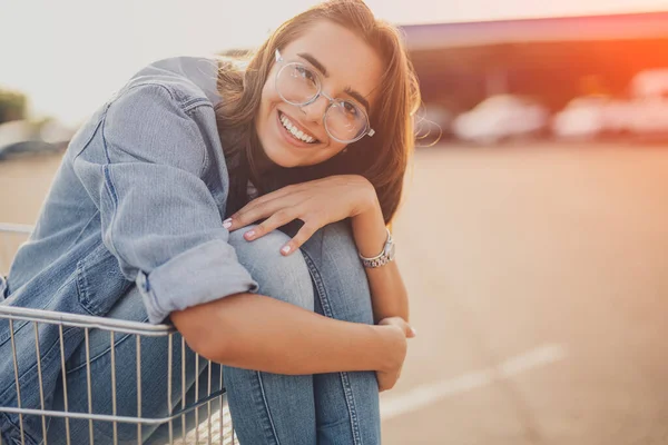 快乐的年轻女人坐在购物车里 — 图库照片