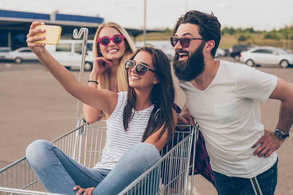 Allegro giovani amici con carrello della spesa prendendo selfie sulla strada — Foto Stock