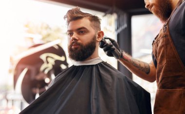 Berber erkek müşteriyle çalışıyor.