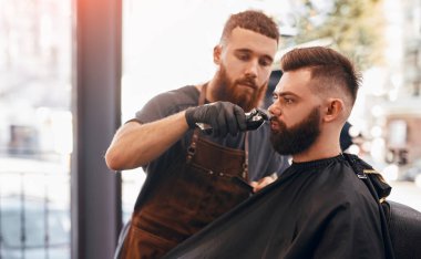 Berber kuaförde müşteriyle çalışıyor.
