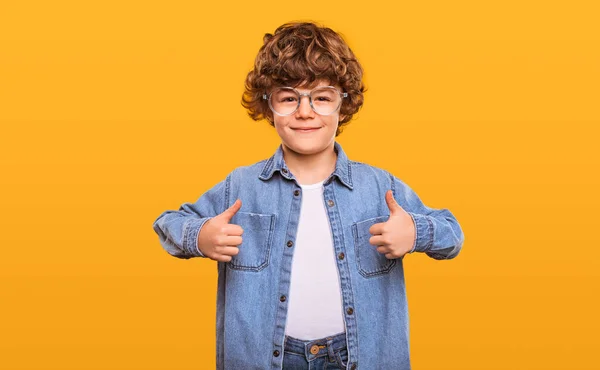 Щасливий школяр в джинсовій сорочці показує великі пальці вгору — стокове фото