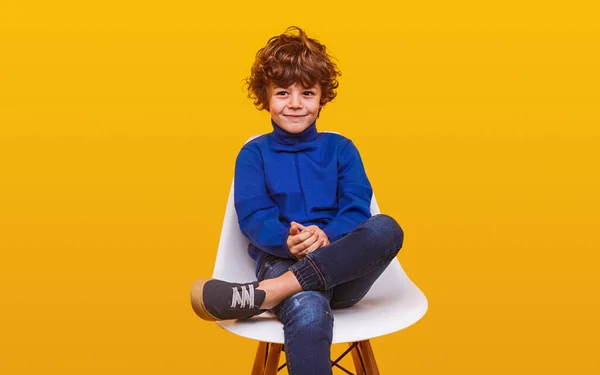 편한 옷을 입고 의자에 앉아 있는 긍정적 인 소년 — 스톡 사진