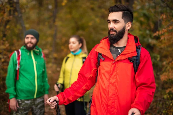 Mochileros jóvenes en chaquetas calientes explorando el bosque de otoño — Foto de Stock