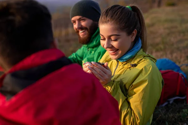 Felices excursionistas disfrutando del té caliente durante el trekking en la naturaleza — Foto de Stock