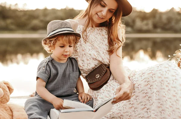 Matka i syn czytają książkę nad jeziorem — Zdjęcie stockowe